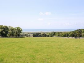 A scenic outdoor area with grass and trees overlooking the ocean at Ysgubor Newydd Parc Isaf Dyffryn Ardudwy