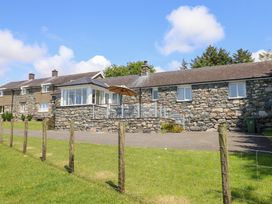 A stone house with a deck and grass area at Ysgubor Newydd Parc Isaf Dyffryn Ardudwy