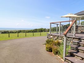 An outdoor area with a deck, chairs, and a view of the sea at Ysgubor Newydd Parc Isaf in Dyffryn Ardudwy