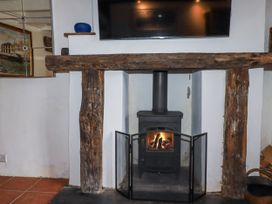 A living room with a fireplace and TV at Rose Cottage, Falmouth