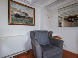 A living room with a painting and an armchair at Rose Cottage in Falmouth
