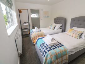 A bedroom with two beds and a wardrobe at Miramar in St. Ives