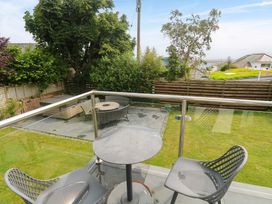 A balcony overlooking a garden with a table and chairs at Miramar in St. Ives