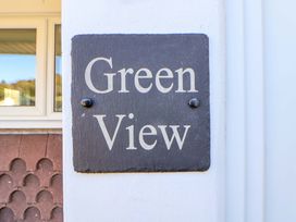 A black sign with white text reading Green View mounted on a white wall near a window