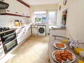 A kitchen with white cabinets oven washing machine and a table with croissants and orange juice at Green View in Llangollen