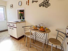 A kitchen with a small table set with croissants drinks and cups and two chairs at Green View in Llangollen