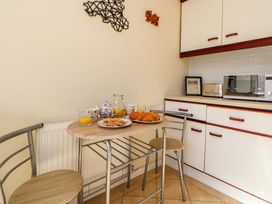 A small kitchen corner with a table and two chairs croissants and plates of pancakes on the table microwave toaster and cupboards on counter at Green View in Llangollen