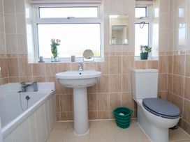 A bathroom with a bathtub sink toilet small mirror and windows with plants at Green View in Llangollen