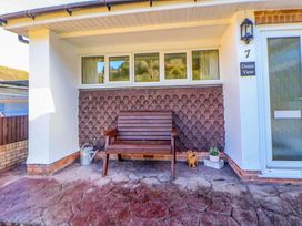 A porch area with a wooden bench a watering can and a small plant pot at Green View in Llangollen