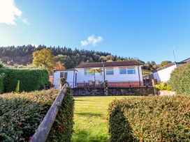 A house with a patio table and umbrella in a garden with trimmed hedges and trees in the background at Green View in Llangollen
