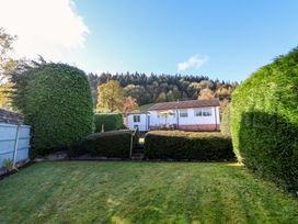 A backyard with a lawn hedge and a house with a patio and outdoor furniture at Green View in Llangollen