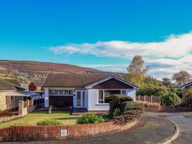 A detached single story house with a front garden and a low brick wall in a residential area at Green View in Llangollen