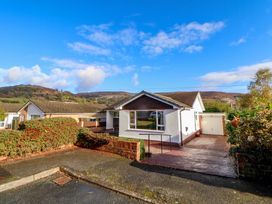 A single-story house with a driveway garage and bushes under a blue sky at Green View in Llangollen