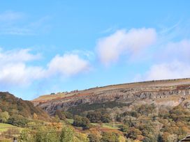 A hillside with trees and rocky cliffs under a blue sky at Green View in Llangollen
