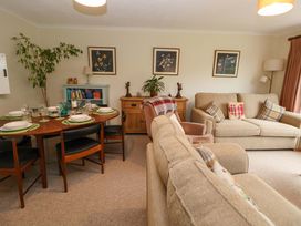 A living room with dining table set with plates and glasses two beige sofas armchair and framed pictures on the wall at Green View in Llangollen