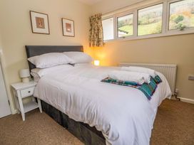 A bedroom with a double bed white bedding rolled towels on a blanket bedside table lamp and framed pictures on the wall at Green View in Llangollen