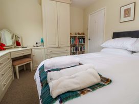A bedroom with a bed with folded towels a plaid blanket a wardrobe a bookshelf and a dressing table at Green View in Llangollen