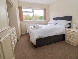 A bedroom with a double bed with white linens two bedside tables with lamp a window with brown blinds and built in wardrobes at Green View in Llangollen