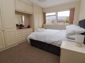 A bedroom with a bed, bedside table with a lamp, built-in wardrobes, and a window showing a view outside at Green View in Llangollen