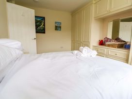 A bedroom with a bed covered in white sheets rolled towels on top built in wardrobes dresser with basket and items on top at Green View in Llangollen
