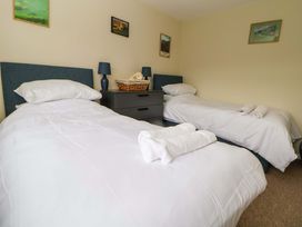 A bedroom with two single beds with white linens a dark nightstand with lamps and a stuffed animal on top at Green View in Llangollen