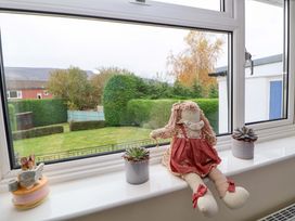 A window sill with a doll in a red dress a small mouse figurine reading a book and two potted succulents at Green View in Llangollen