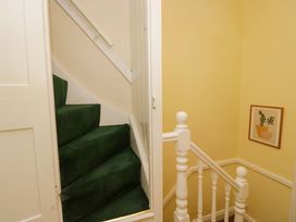 A staircase with green carpet and a painting at 28 Rock Villas in Carnforth