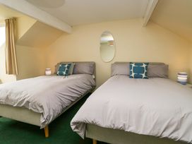 A bedroom with two beds, a mirror, and curtains at 28 Rock Villas Carnforth