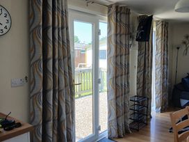 A living room with a door and curtains at Gwanda in Tregolds near St Merryn