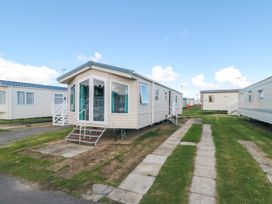 A row of static caravans with steps leading to the doors on a grassy and paved area at 13 Gosling in Cayton Bay