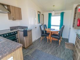 A kitchen and dining area with brown cabinets black chairs and a round wooden table at 13 Gosling in Cayton Bay