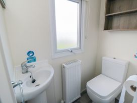 A small bathroom with a toilet sink radiator and a window at 13 Gosling in Cayton Bay