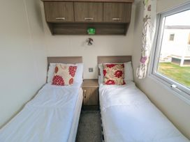 A bedroom with two single beds separated by a nightstand and a window at 13 Gosling in Cayton Bay