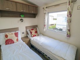 A bedroom with two single beds bedside table and wall cabinets at 13 Gosling in Cayton Bay
