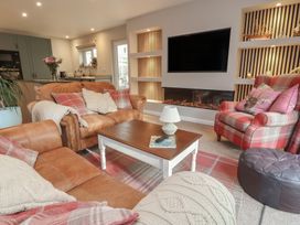A living room with a sofa, armchair, coffee table, and television at Little Willesleigh in Goodleigh near Barnstaple