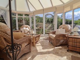 A conservatory with rattan chairs and a coffee table at Little Willesleigh in Goodleigh near Barnstaple