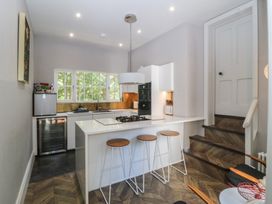A kitchen with stove and bar stools at Gweryl Lodge in Conwy