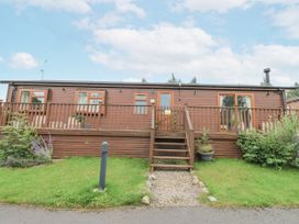 A cabin with a deck and steps at Butterfly Lodge in Tunstall near Catterick, North Yorkshire