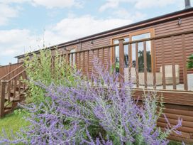An outdoor view of a cabin with a flower bed and steps at Butterfly Lodge in Tunstall near Catterick, North Yorkshire