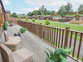 An outdoor deck with chairs and planters at Butterfly Lodge in Tunstall near Catterick, North Yorkshire