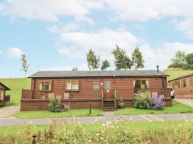 A lodge with a deck and windows at Butterfly Lodge in Tunstall near Catterick, North Yorkshire