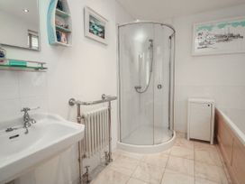 A bathroom with a sink, shower, radiator, and bath at Full Deck in Dartmouth