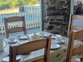 A dining room with a set table and stone wall at Bryn Y Garreg Cottage - The Wireless Free Farm near Llangadfan