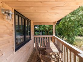 A wooden covered balcony with a table and chairs overlooking trees at Walden Lodge in Tresillian Wood near Llantwit Major