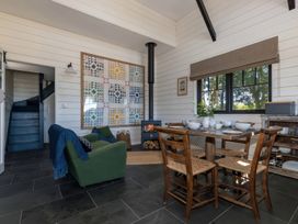 A dining area with wooden table and chairs and a green sofa near a wood burning stove and staircase at Walden Lodge Tresillian Wood near Llantwit Major