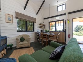 An open living and dining area with a green sofa an armchair dining table and kitchen at Walden Lodge Tresillian Wood near Llantwit Major