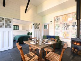 A dining area with wooden table and chairs next to a wood stove and bed in adjacent room at Walden Lodge in Tresillian Wood near Llantwit Major