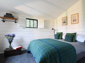 A bedroom with a bed and green and blue bedding a small window and a vase of flowers on a chest at Walden Lodge Tresillian Wood near Llantwit Major