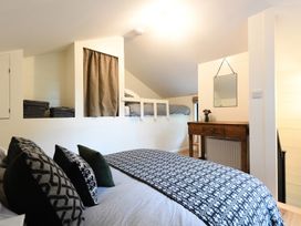 A bedroom with a bed, pillows, a wooden desk with flowers, a mirror on the wall, and a raised sleeping area at Walden Lodge Tresillian Wood near Llantwit Major