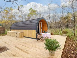 A wooden cabin on a deck with a table and chairs in an outdoor wooded area at Hobhole in Keal Cotes near East Kirkby